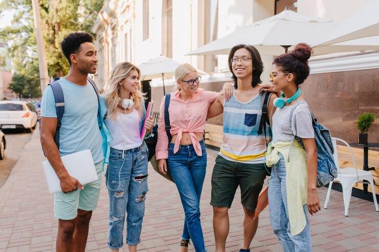 Heureux etudiants ecoutant ami asiatique lunettes qui raconte nouvelle blague filles portent jeans ecouteurs mode passant du temps camarades dans rue cote du cafe 197531 3868